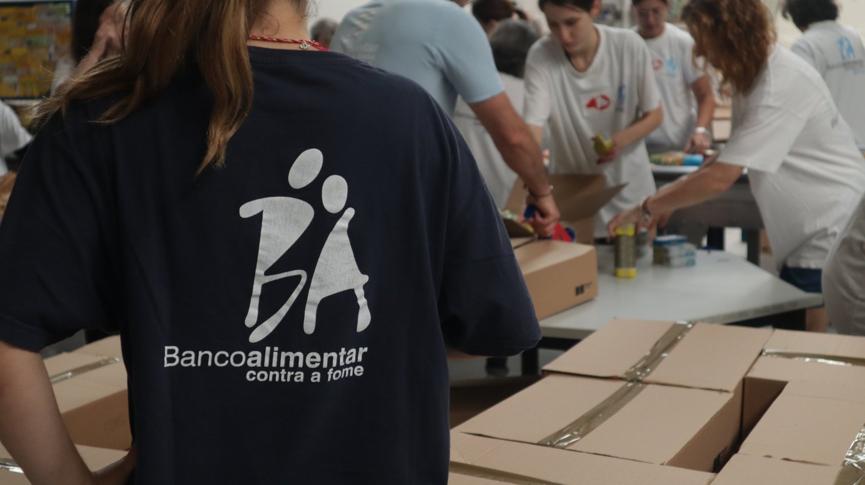 Voluntária de costas com t-shirt do Banco Alimentar Contra a Fome a trabalhar no armazém durante uma campanha